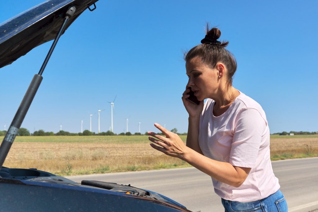Car breakdown, unhappy woman on the road talking on mobile phone